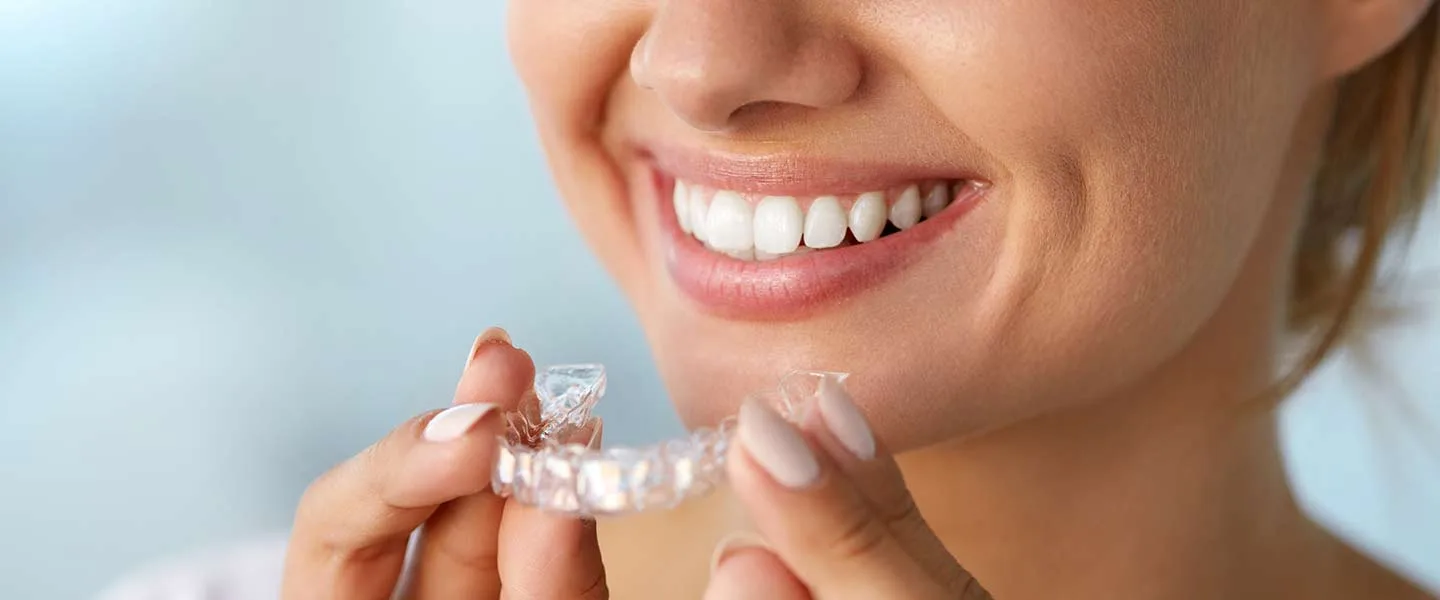 Patient holding Invisalign clear aligner trays at Krutav Patel DDS in Claremont